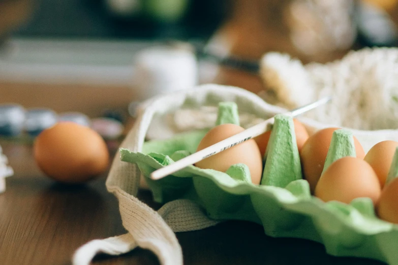 a basket of eggs sitting on top of a wooden table, a still life, trending on pexels, green and brown clothes, baking a cake, cutlery, thumbnail