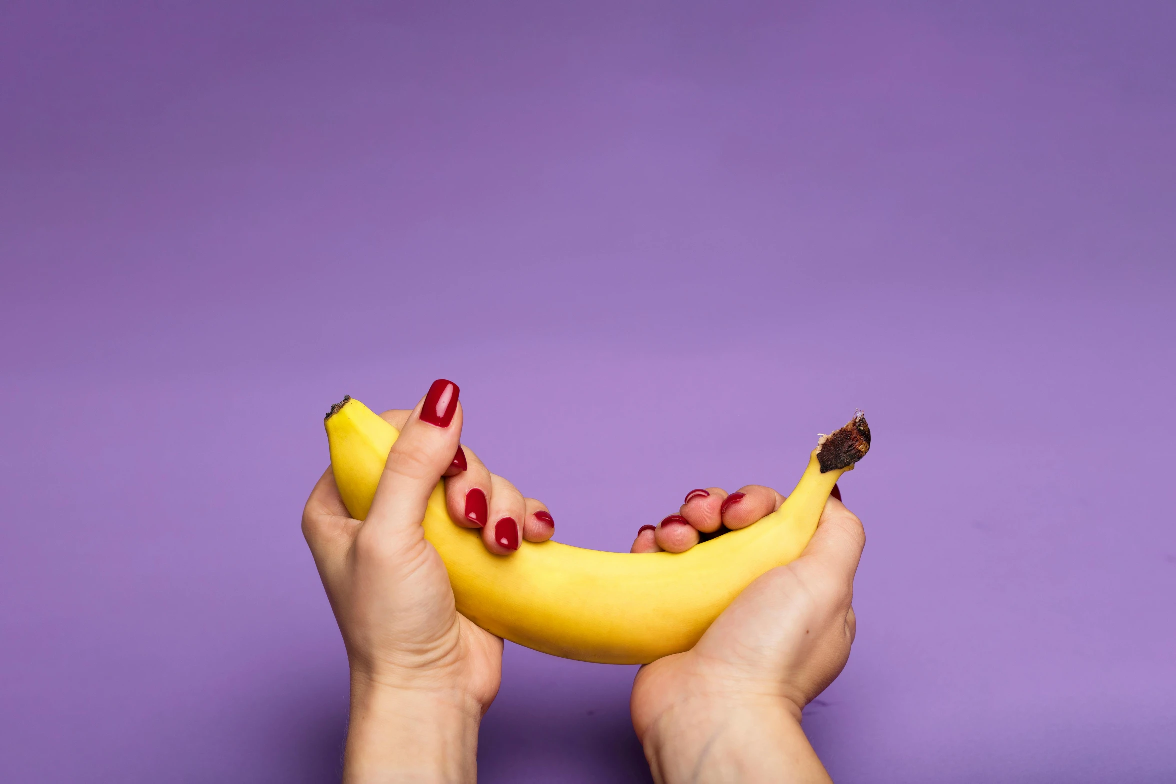 a person holding a banana in their hands, by Julia Pishtar, purple, adult video store, solid background, high quality product image”