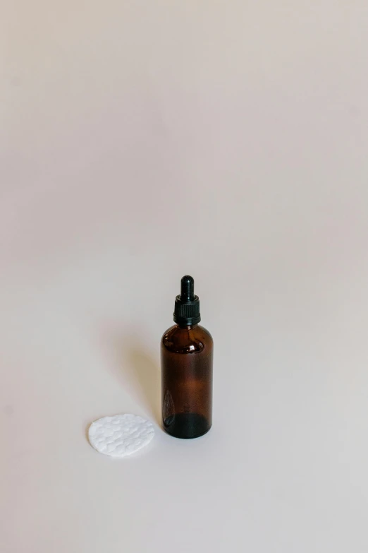 a bottle of essential oil on a white surface, unsplash, brown, round format, thumbnail, foam