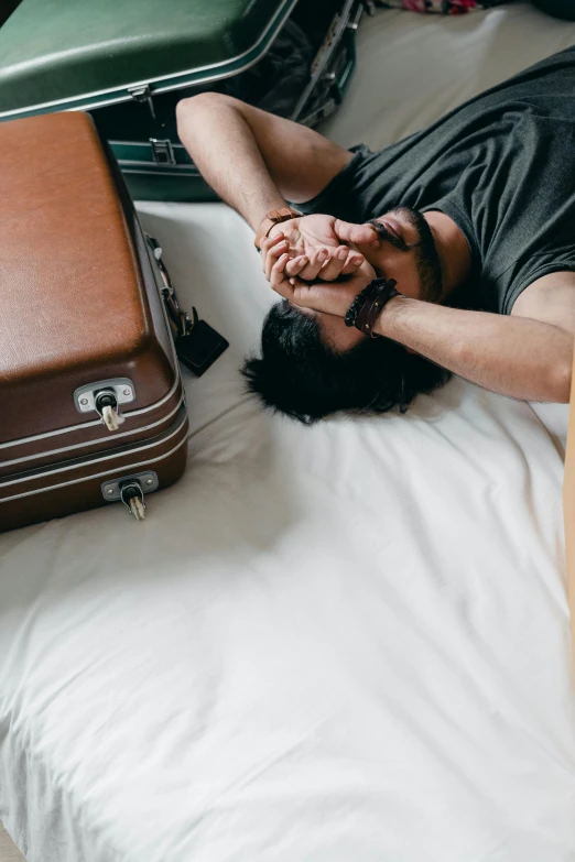 a man laying on top of a bed next to luggage, pexels contest winner, happening, hands shielding face, gif, ignant, upset