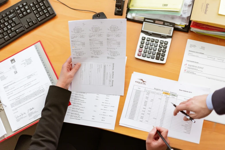 a person sitting at a desk with papers and a calculator, customers, rhys lee, thumbnail, bottom angle