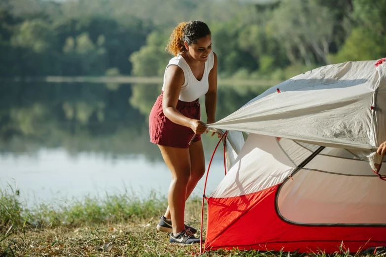 a woman setting up a tent next to a lake, white and red color scheme, fan favorite, sturdy body, profile image