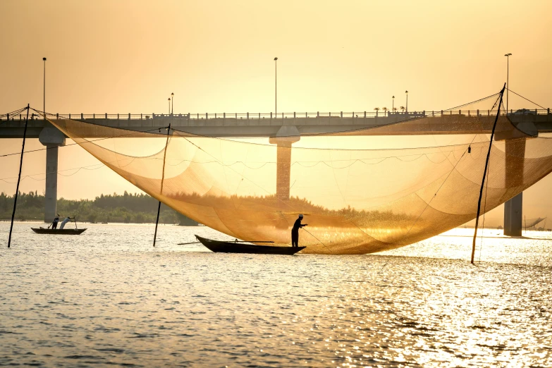 a man standing on top of a boat next to a bridge, by Jan Tengnagel, pexels contest winner, golden hues, nets, in style of lam manh, sail made of human skin