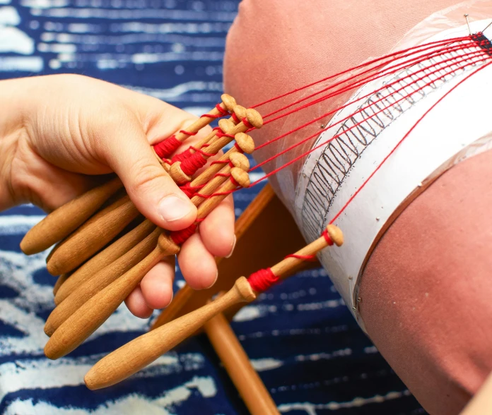 a close up of a person holding a bunch of sticks, an album cover, inspired by Louise Bourgeois, unsplash, weaving, garters, acupuncture treatment, red and blue garments