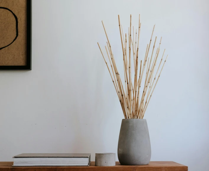 a vase sitting on top of a wooden table, inspired by Inshō Dōmoto, unsplash, tiny sticks, smooth concrete, made of bamboo, detailed product shot