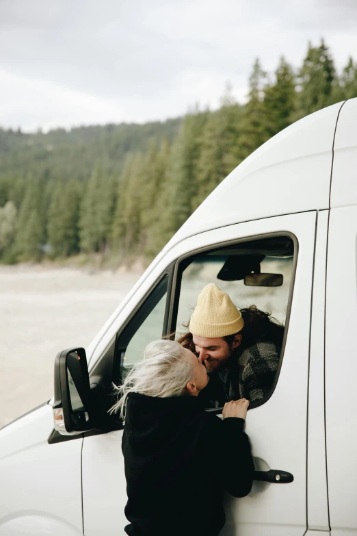 a man kissing a woman in the driver's seat of a van, a photo, by Jessie Algie, trending on unsplash, idaho, victoria siemer, hugging, hat covering eyes