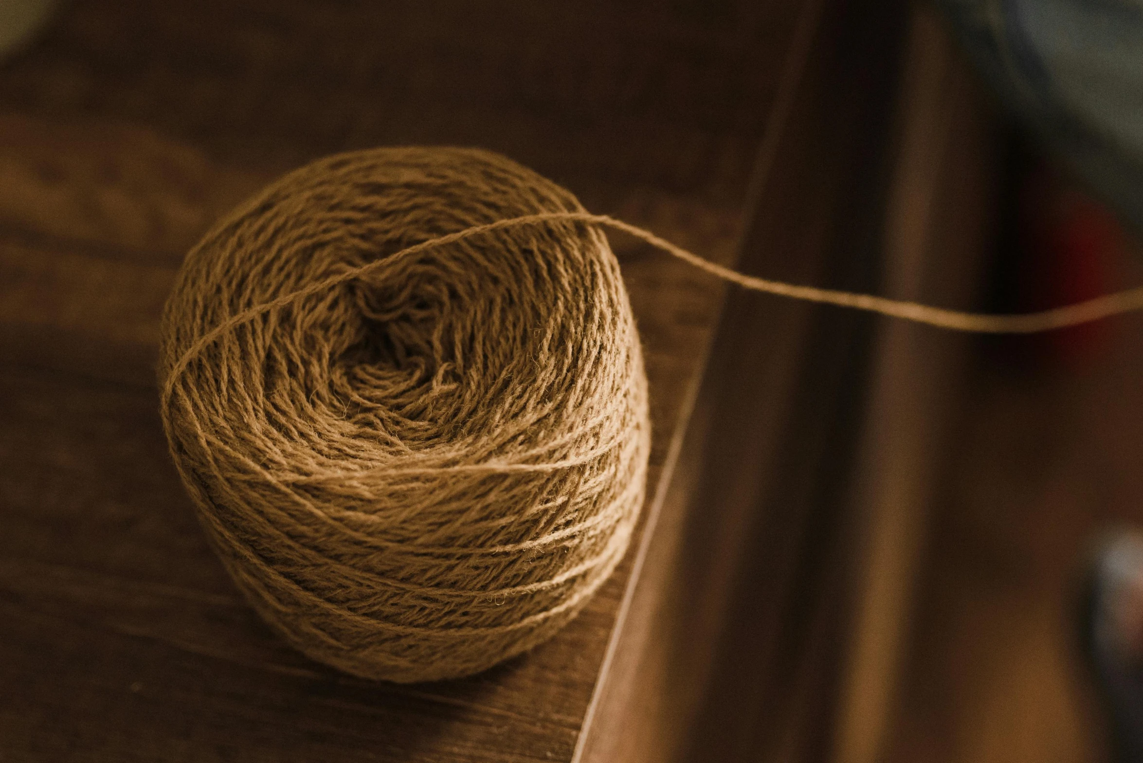 a ball of yarn sitting on top of a wooden table, inspired by Inshō Dōmoto, unsplash, arts and crafts movement, light brown, brown, medium, burlap