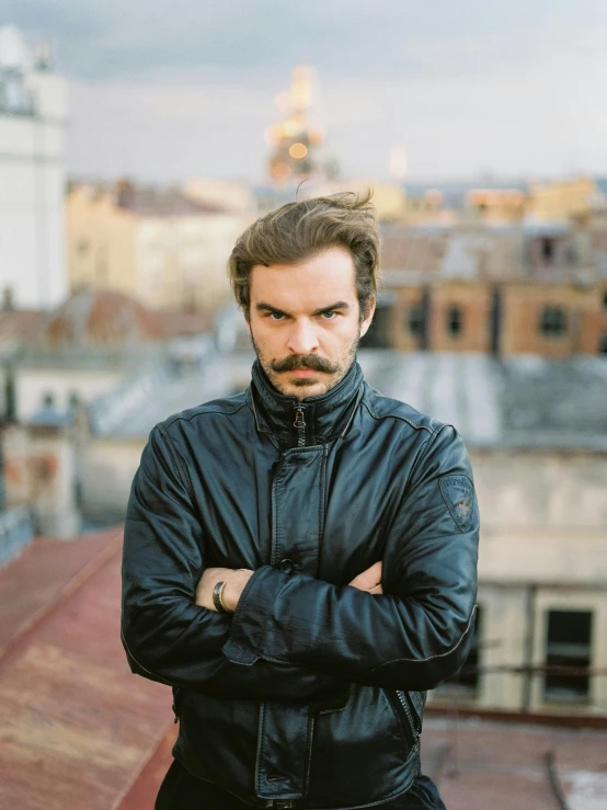 a man standing on top of a roof with his arms crossed, by Adam Szentpétery, handlebar mustache, wearing a turtleneck and jacket, jovana rikalo, thick jawline