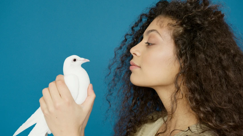 a woman holding a white bird in her hand, a surrealist sculpture, trending on pexels, magic realism, silicone skin, looking from side, trending on dezeen, light from right