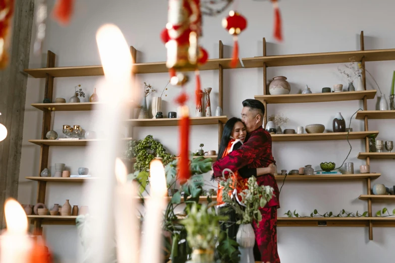 a man and woman standing next to each other in a room, by Julia Pishtar, pexels contest winner, chinese new year in shanghai, hugging, decorations, profile image