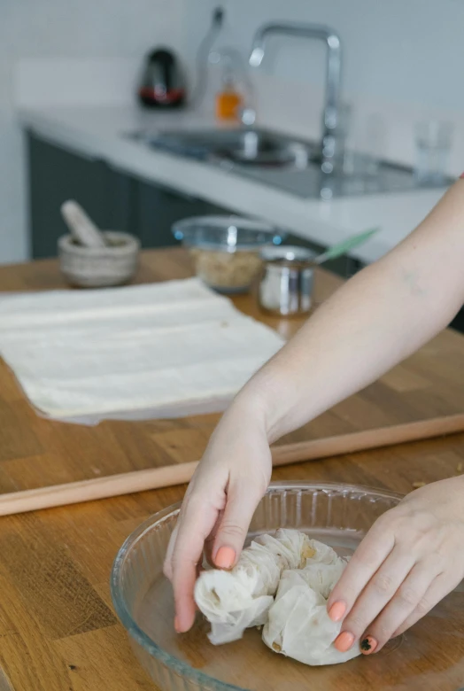 a woman making dumplings in a bowl on a kitchen counter, trending on pexels, process art, baking french baguette, square, banner, low quality photo