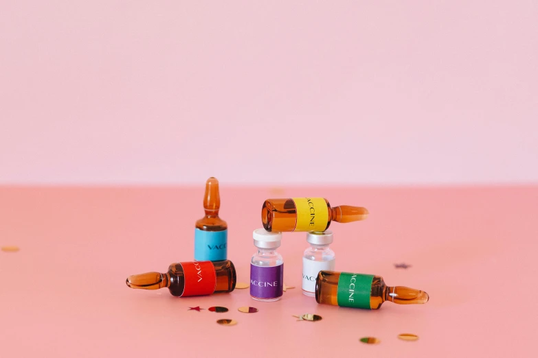a group of bottles sitting on top of a pink surface, antipodeans, rainbow coloured rockets, acne, product shot, acupuncture treatment