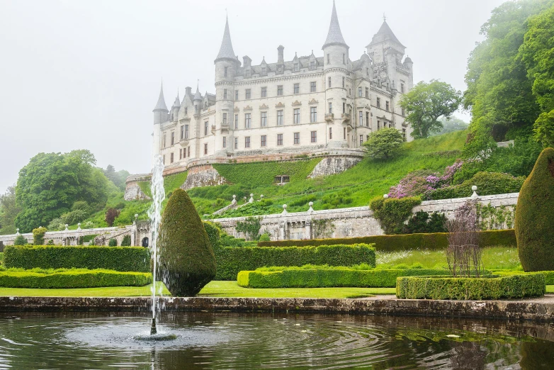 a large castle sitting on top of a lush green hillside, pexels contest winner, art nouveau, featuring marble fountains, julia hetta, scottish highlands, exterior botanical garden