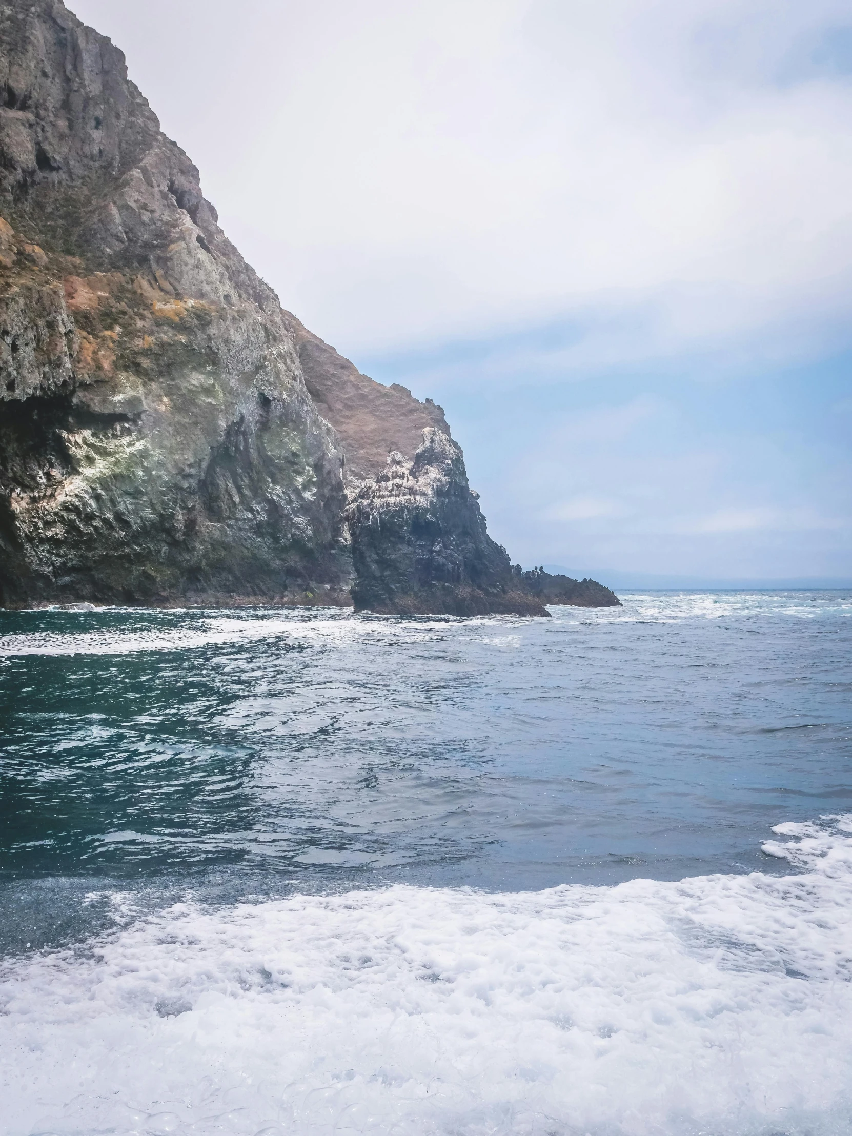 a man riding a wave on top of a surfboard, in the distance is a rocky hill, pch, photo taken from a boat, skull island