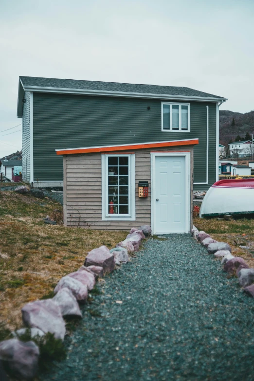 a small building with a boat parked in front of it, by Jessie Algie, unsplash, private press, orange grey white, trailer park, sloped site, official store photo