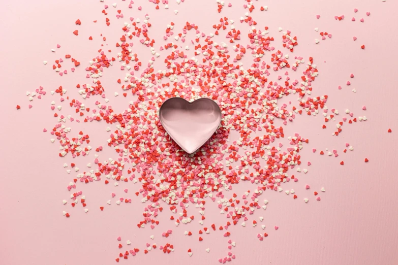 a heart shaped box surrounded by confetti sprinkles, by Julia Pishtar, visual art, petal pink gradient scheme, made out of shiny silver, sweets, lying scattered across an empty