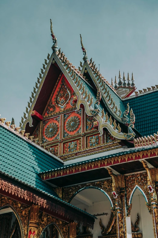 a close up of a building with a clock on it, thai temple, prussian blue and venetian red, simple gable roofs, intricate detailed roof