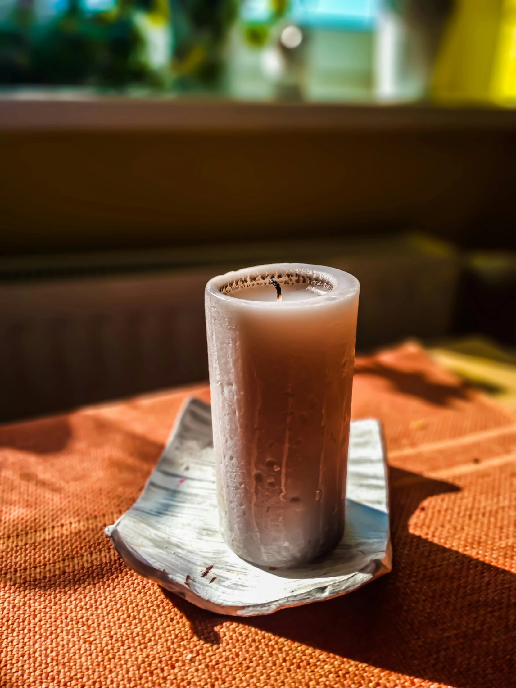 a glass of milk sitting on top of a table, incense, warm sunlight shining in, wet clay, on a candle holder