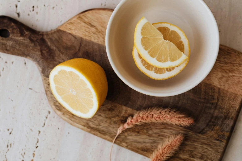 a bowl of lemons sitting on top of a cutting board, trending on pexels, with a white mug, botanicals, background image, crisp details