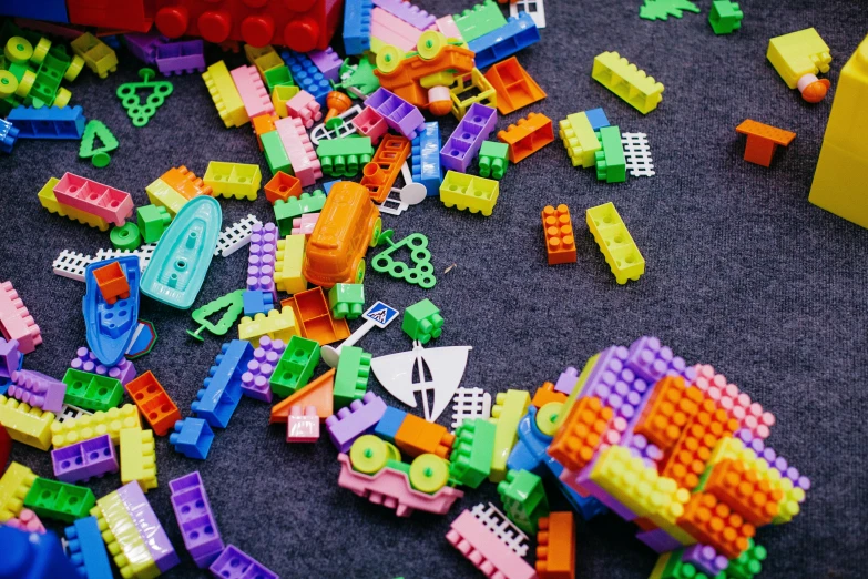 a pile of legos sitting on top of a table, broken toys are scattered around, with fluo colored details, thumbnail, square