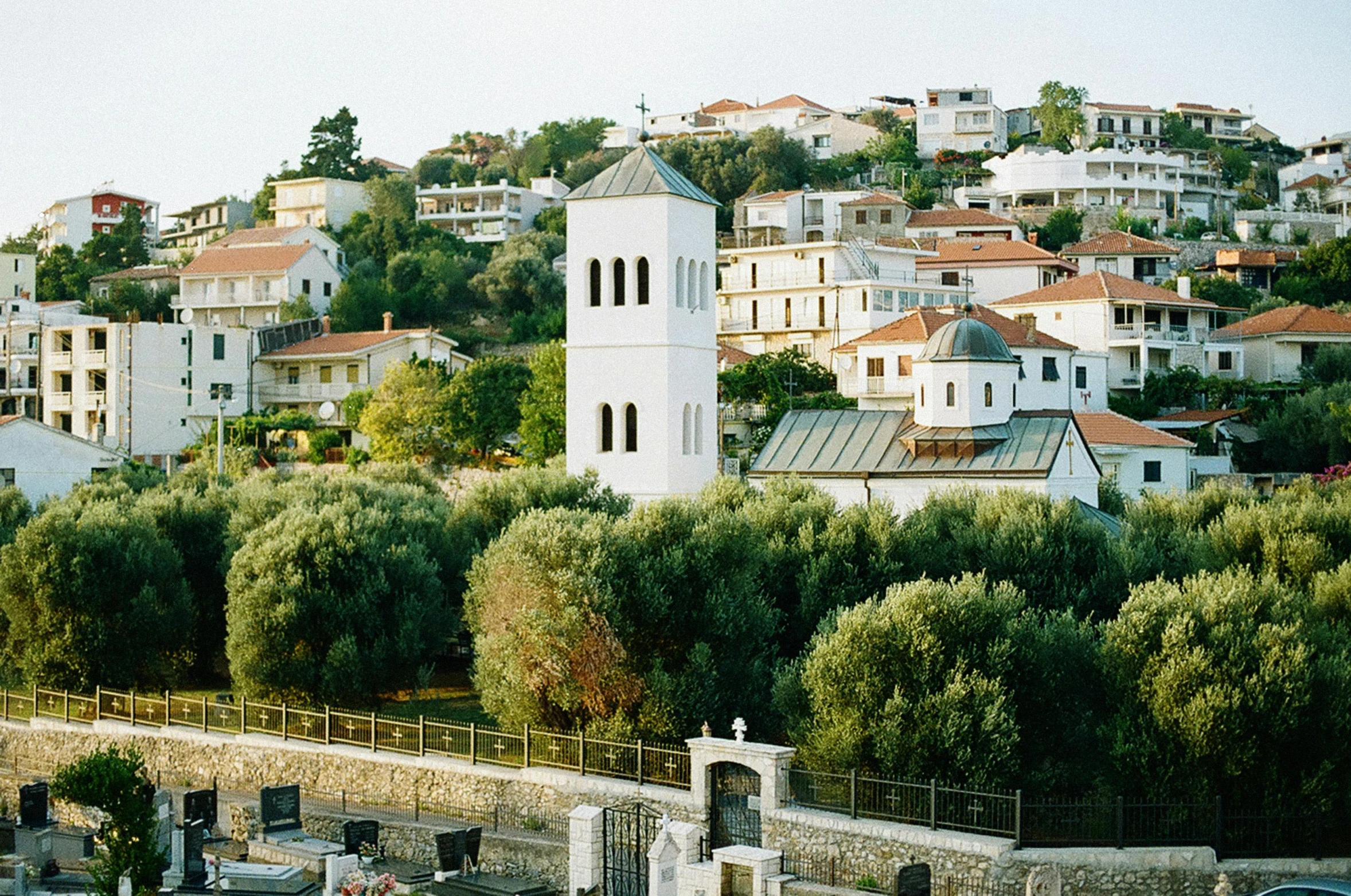 a large white church sitting on top of a lush green hillside, pexels, mediterranean fisher village, 1990s photograph, square, athene