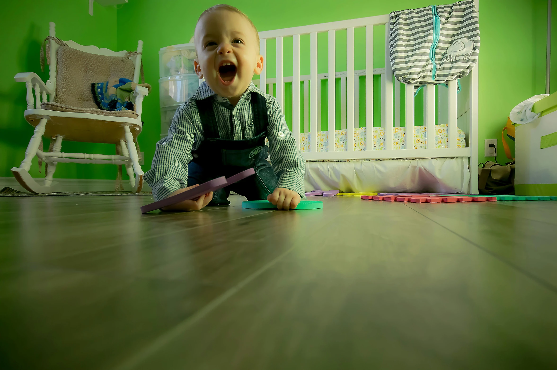 a baby sitting on the floor in front of a crib, pexels contest winner, pop art, excited expression, green floor, 15081959 21121991 01012000 4k, blurred