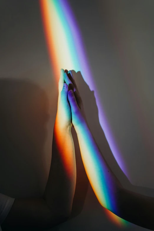 a person touching a rainbow on a wall, trending on pexels, light and space, praying, refracted lighting, hands pressed together in bow, bisexual lighting