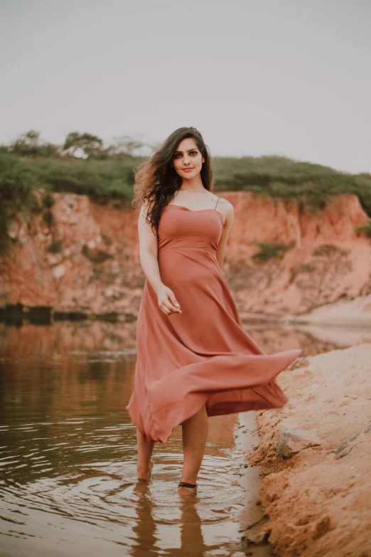 a woman standing in a body of water, by Rose Henriques, pexels contest winner, renaissance, beautiful silky dress, brazil, warm muted colors, casual pose