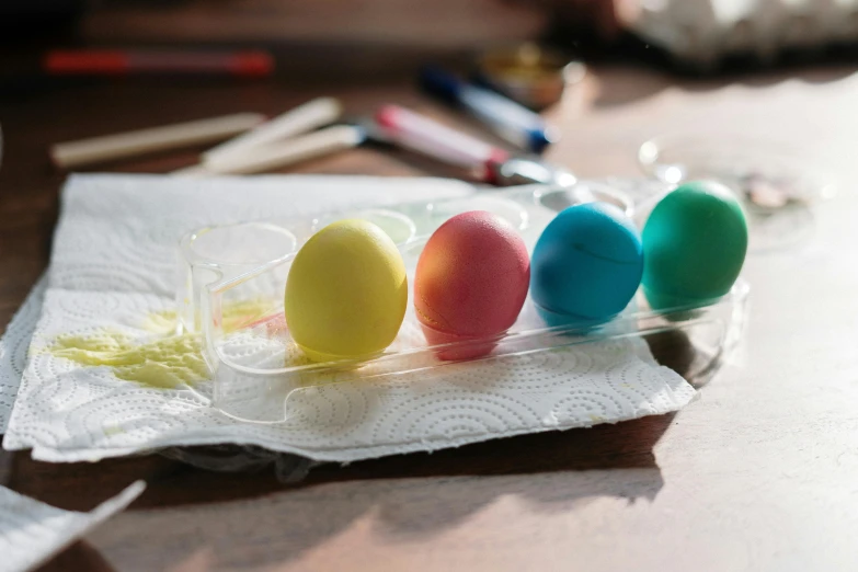 a group of colored eggs sitting on top of a table, by Sylvia Wishart, trending on pexels, process art, paint tubes, morning sunlight, easter, recipe