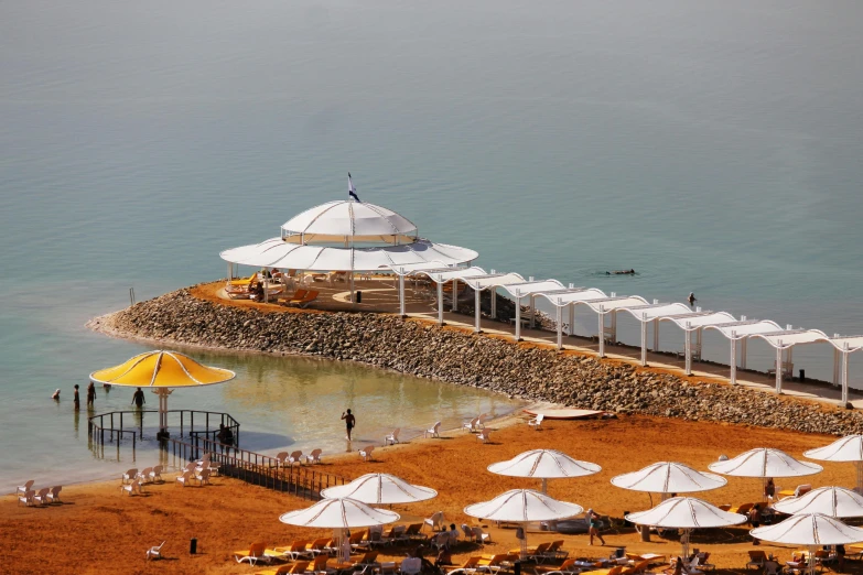 a group of umbrellas sitting on top of a sandy beach, dau-al-set, the dead sea, futuristic persian palace, circular, slide show