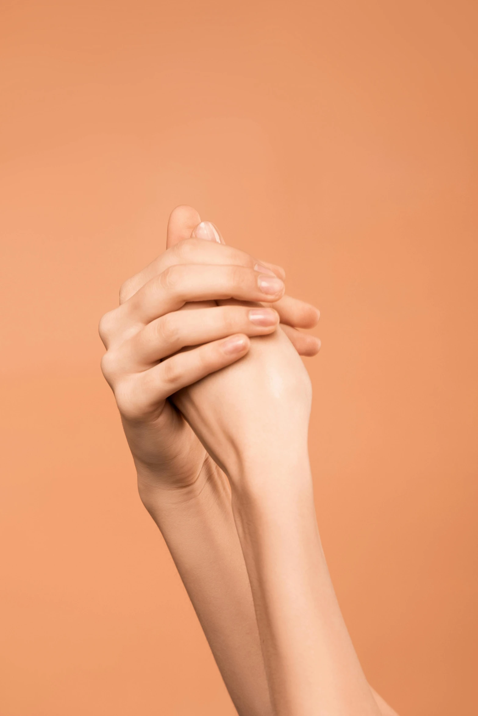 a close up of a person holding their hands together, by Gavin Hamilton, in shades of peach, skincare, praying posture, plain background