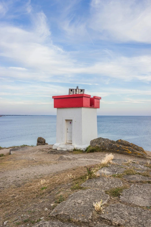 a red and white lighthouse sitting on top of a rock, next to the sea, slide show, lightbox, grey