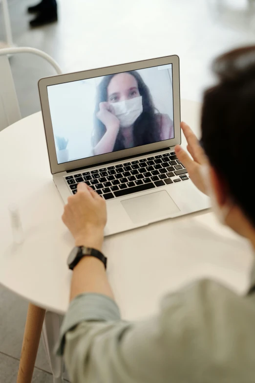 a person sitting at a table with a laptop, mask off, picture through the screen, in meeting together, promo image