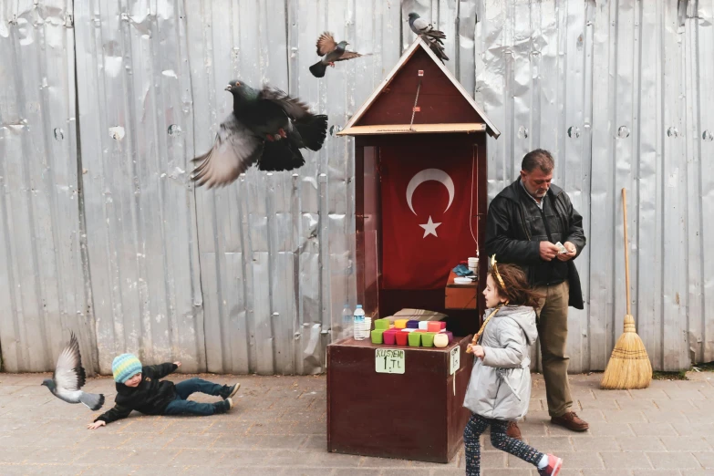 a man standing next to a little girl in front of a bird house, by irakli nadar, world press photo awarded, turkey, sitting on a miniature city, people watching