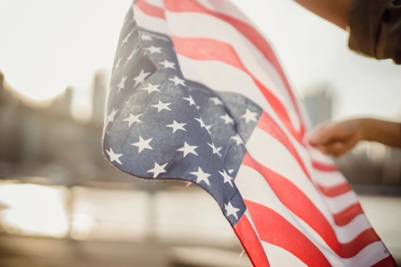 a person holding an american flag near a body of water, profile image, 🚿🗝📝