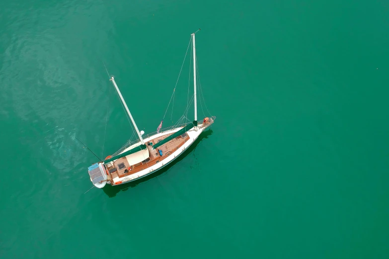 a boat that is floating in the water, overhead birdseye view, he's on an old sailing boat, green waters, rich colour