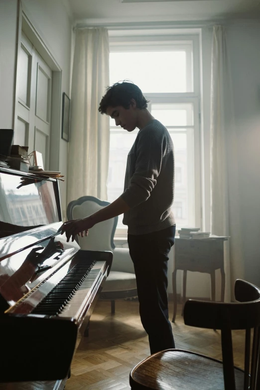 a man standing next to a piano in a living room, by Vadym Meller, pexels contest winner, movie still, orelsan, robert sheehan, helsinki