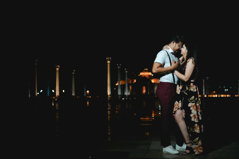 a couple standing next to each other on a dock at night, a portrait, pexels contest winner, in persian temple wet night, profile image, sassy pose, youtube thumbnail