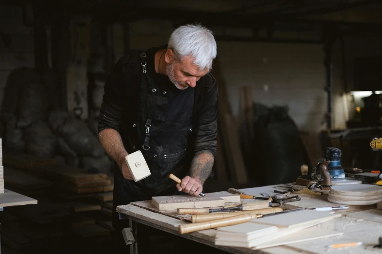 a man is working on a piece of wood, inspired by Constantin Hansen, trending on unsplash, arts and crafts movement, lee griggs, grey, rectangle, celebrating