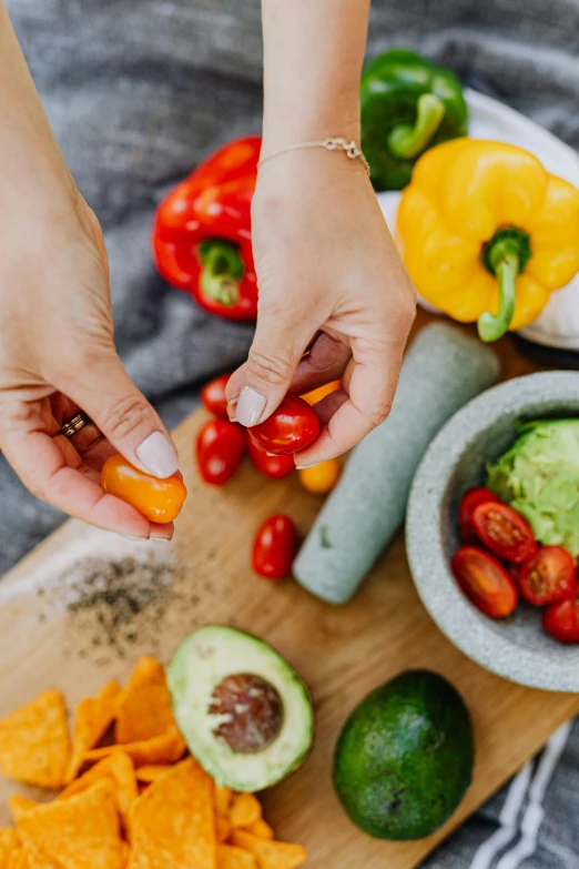 a person cutting up vegetables on a cutting board, by Julia Pishtar, ingredients on the table, colombian, grey, multicoloured