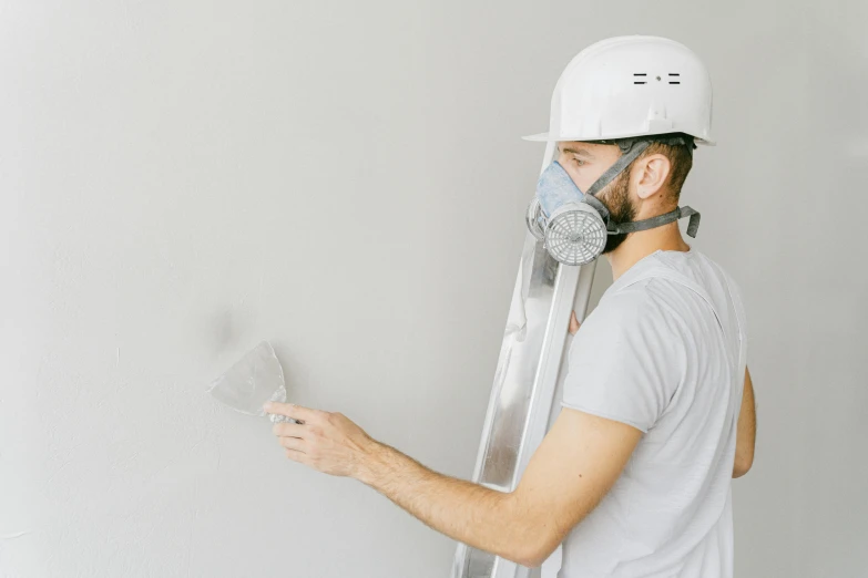 a man in a white helmet painting a wall, by Andries Stock, pexels contest winner, arbeitsrat für kunst, grey mist, face mask, background image, white background and fill