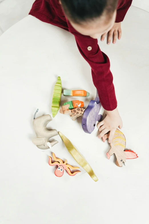 a young boy playing with toys on a table, inspired by Sarah Lucas, unsplash, liana wrap two fantasy creatures, detail shot, ribbon, on a white background