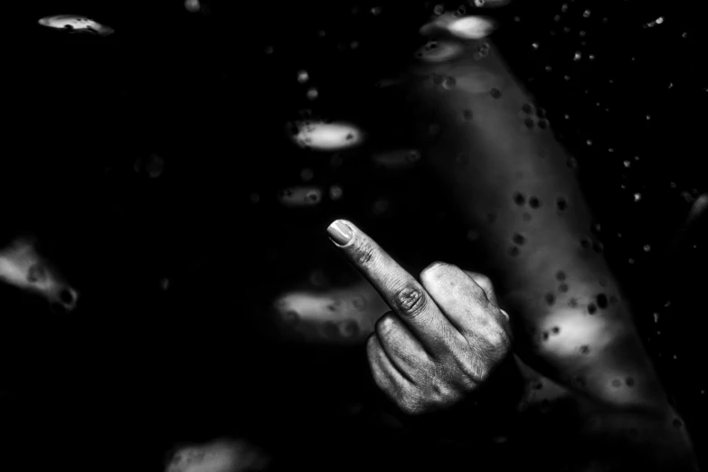 a black and white photo of a hand pointing at something, an album cover, unsplash, art photography, carnal ) wet, water water, giving the middle finger, violence