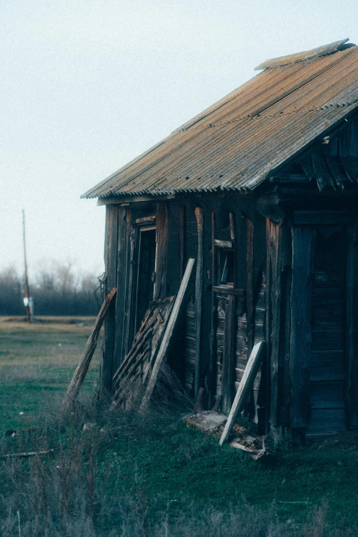 an old shack sitting in the middle of a field, inspired by Elsa Bleda, unsplash, renaissance, background image, color image, 1990s photograph, buildings covered in black tar