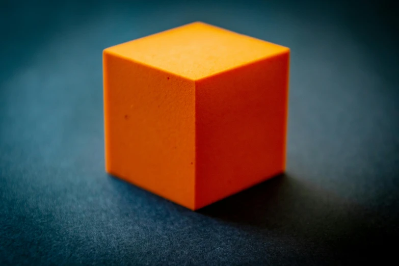 an orange cube sitting on top of a blue surface, profile pic, platonic solids, miscellaneous objects, solid shapes