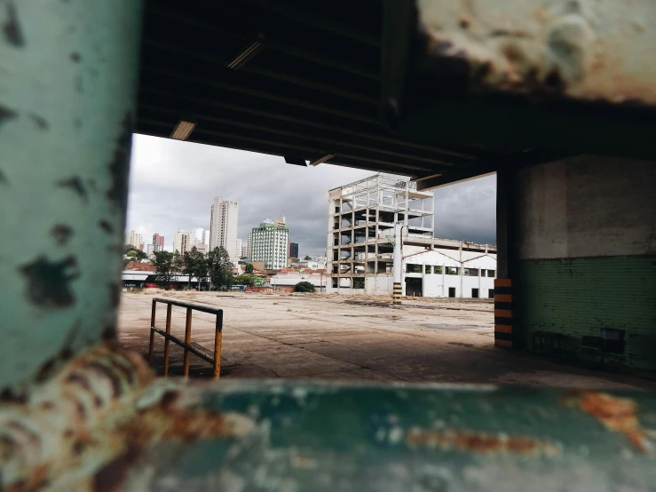 a view of a city through a hole in a wall, pexels contest winner, brutalism, empty warehouse background, in sao paulo, shipyard, 90s photo