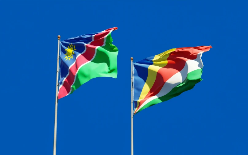 two flags blowing in the wind against a blue sky, by Hubert van Ravesteyn, unsplash, hurufiyya, multi colored, rendered in 4 k, avatar image, merged machima