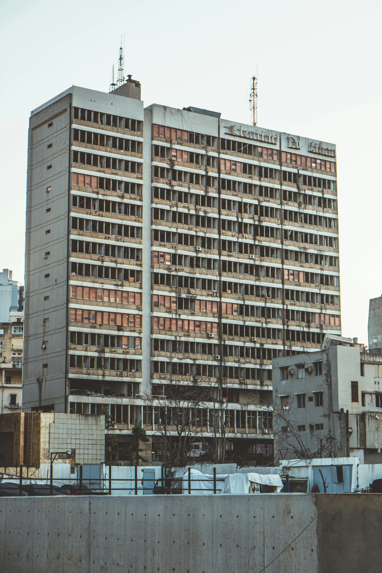 a tall building sitting in the middle of a city, a colorized photo, brutalism, tehran, government archive photograph, front side, partially operational