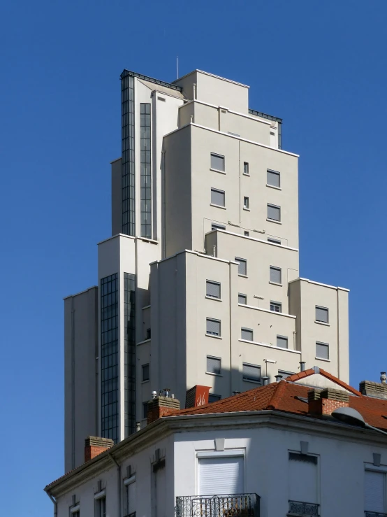 a tall building with a clock on top of it, inspired by János Nagy Balogh, built on a steep hill, art deco era)