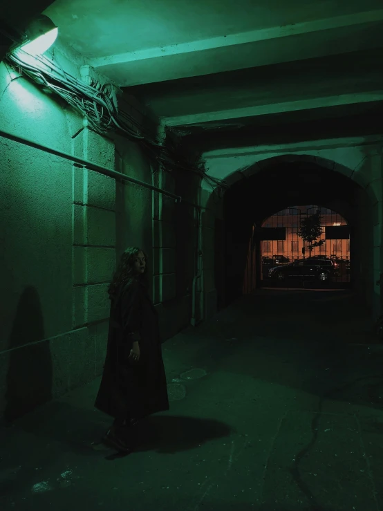 a person standing in a dark hallway at night, an album cover, inspired by Elsa Bleda, pexels contest winner, green cape, cyberpunk city street, vantablack wall, low quality photo